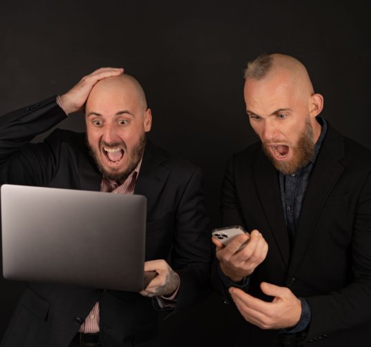 Two brutal bearded men in suits on a black background scream with happiness, rejoice, the cryptocurrency has grown, businessmen with a laptop